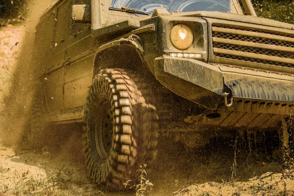 Veículo offroad saindo de um perigo de buraco de lama. Vista inferior para grande roda offroad carro no país estrada e montanhas pano de fundo. Viagens off-road na estrada de montanha . — Fotografia de Stock