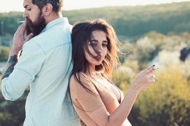 Açık havada, Sigara rahat yüzündeki defocused arka plan, doğa birkaç. Erkek ve kadın bahar gününde sigara tutar. Aşık çift harcamak zaman açık havada ve yasaktır. Sigara alışkanlığı kavramı.