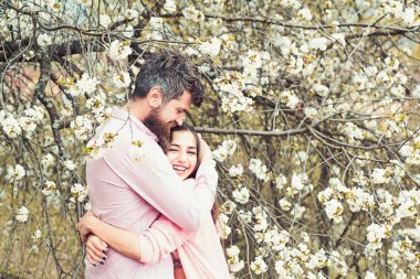 Bahar tarihi kavramı. Çift çiçek açan ağaçlar sarılmak. Çiçek Bahçe erkek ve kadın hugs bahar gününde. Aşık çift bahar bahçe, dalları zemin üzerine çiçekli zaman harcamak.