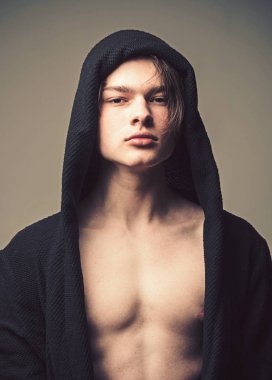 Siyah hood, gri arka planda emin yüz adam. Erkeklik kavramı. Maço siyah bornoz ile kukuleta, yakın çekim. Pürüzsüz cilt üzerinde yüz, boyun ve göğüs kameraya bakarak adam.
