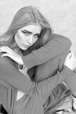 Kalın kaşları ve kızardı yanakları yere oturma portre sarışın model. Parlak kıyafeti açık havada poz içinde kız