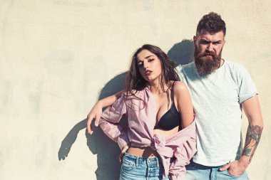 Sakal ve Bayan sıcak güneşli günde kibirli yüzünde olan adam. Çift ısı yaz gününde, arka plan, kopya alanı duvarda uğrar. Kız açılarak forması altında siyah sutyen takıyor. Sıcak ve seksi kavramı.