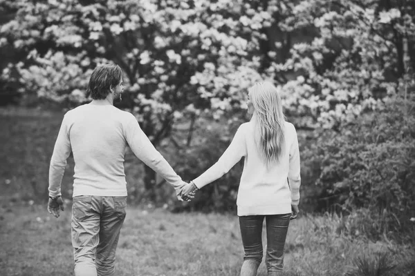 Girlfriend and boyfriend hold hands in spring park, back view — Stock Photo, Image