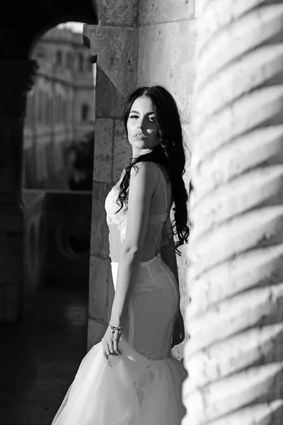 Beautiful bride stands at the stone column. — Stock Photo, Image