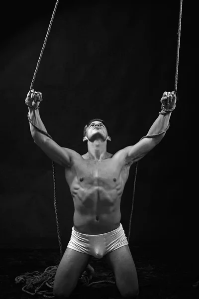 Man with muscular body on rope. Circus gymnast at pilates or yoga training. Sport workout for bodybuilder. Fitness dieting and flexibility in acrobatics. Sexy macho man do gymnastic. — Stock Photo, Image