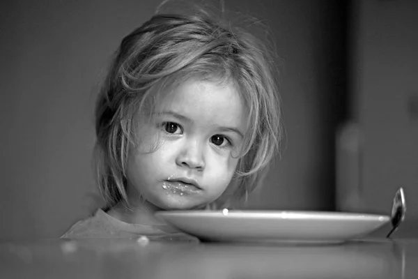 Gyermek az üres tányért, kanállal evés után — Stock Fotó