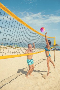 Spor aktivite ve sağlık. Aşık çift güneşli kumsalda voleybol oynuyorsun. Seksi kadın ve net baloda kaslı adam. Yaz tatili ve Miami tatil seyahat. Aşk ve flört birkaç