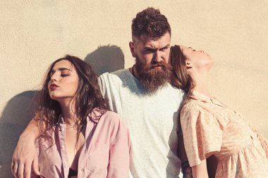 Sakallı adam sıcak güneşli günde iki Bayan sarılmak. Üçlü ısı yaz gününde, arka duvarda uğrar. Adam onları hugs iken kızlar ters tarafı için döndü. Aşk üçgeni kavramı