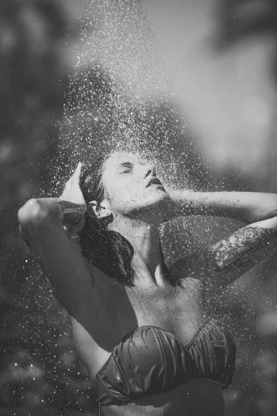 热和茶点的概念。性感的比基尼女士在炎热的晴天享受淋浴。水滴落在迷人的女人身上。游泳后在沙滩上沐浴的年轻漂亮的黑发女孩. — 图库照片