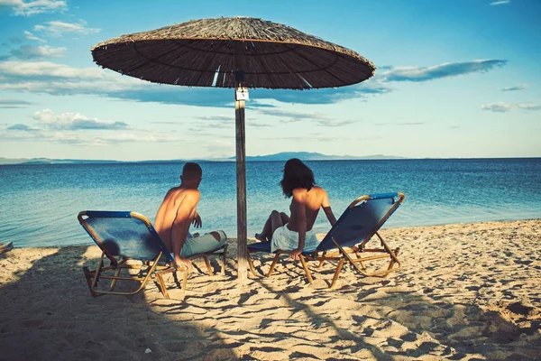 Relaciones amorosas de pareja desnuda en el mar. Familia y día de San Valentín. Pareja enamorada de cuerpo sexy relajarse en la playa. Vacaciones de verano y vacaciones de viaje paraíso. Mujer sexy y hombre bronceado en el paraguas . — Foto de Stock