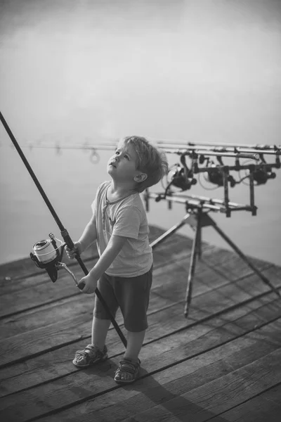 Criança com vara de pesca no cais de madeira — Fotografia de Stock