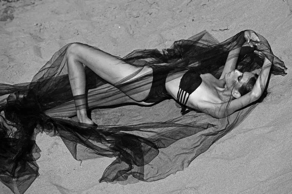 Fashion woman in swimsuit under black veil relax on sand — Stock Photo, Image