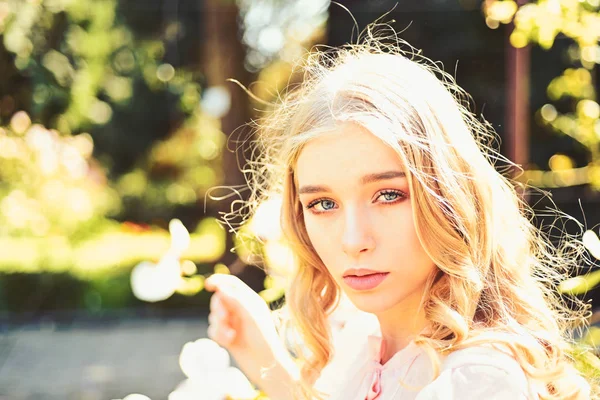 Menina no rosto sonhador, loira terna olha para a câmera, fundo da natureza, desfocada. Lady caminha no parque no dia ensolarado da primavera. Conceito de dia ensolarado. Jovem mulher desfrutar da natureza no jardim . — Fotografia de Stock