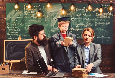 Aile, masada dizüstü bilgisayar ile birlikte çalışma. Dahi oğlu anne ve baba öğrenciler için kitap okuyun. Küçük çocuk okul kadın ve adam ile oynamak. Okula dönüş. Bilgi ve okuma kavramı