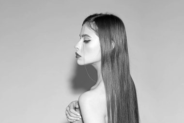 Makyaj ve visage kavramı. Kız çıplak omuz ile kapalı gözlerle sakin yüzündeki ışık mavi arka plan, kopya alanı. Kadın şık makyaj ve saç modeli ile eli göğsünde, yan görünüm tutar.