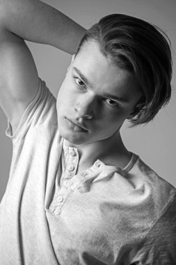 Emin yüz ışık gömlekli adam saçlı, gri arka plan dokunur. Maço şık uzun saç kesimi ile. Adam kameraya bakarak yüzündeki pürüzsüz bir cilt. Kuaför ve saç modeli kavramı.