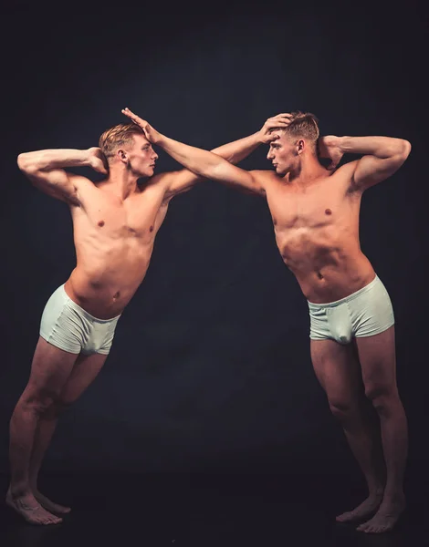 Tvillingar män med muskulös kropp i balans pose. Circus gymnaster på pilates eller yoga utbildning. Sport träning för kroppsbyggare. Fitness bantning och flexibilitet i akrobatik. Vänskap av män gör gymnastiska — Stockfoto