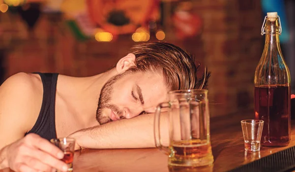 Debería estar preocupado por su hábito. Hombre alcohólico durmiendo en el mostrador del bar. El hombre duerme después de beber bebidas alcohólicas fuertes y cerveza en el pub. Adicto al alcohol con alcohol. Adicción al alcohol —  Fotos de Stock