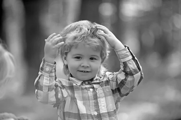 Liten glad pojke leker med lämnar på gyllene höst park bakgrund — Stockfoto