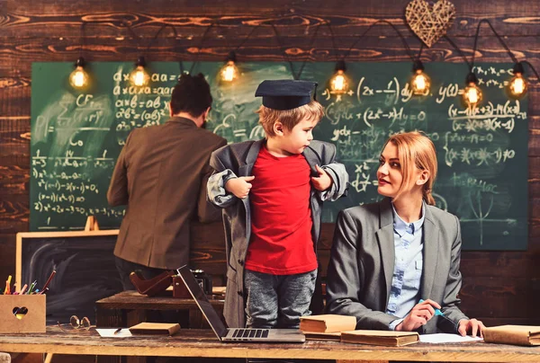 Kid playing game. Home schooling concept. Smart child in graduate cap likes to study. Parents teaching kid at home. Boy presenting knowledge to mom and dad. Parents listening son