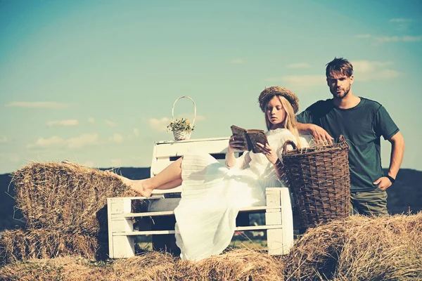 Woman bride in wedding dress relax on bench. Sensual woman read book for man. Couple in love on vacation. Family enjoy summer nature. Girlfriend and boyfriend date outdoor