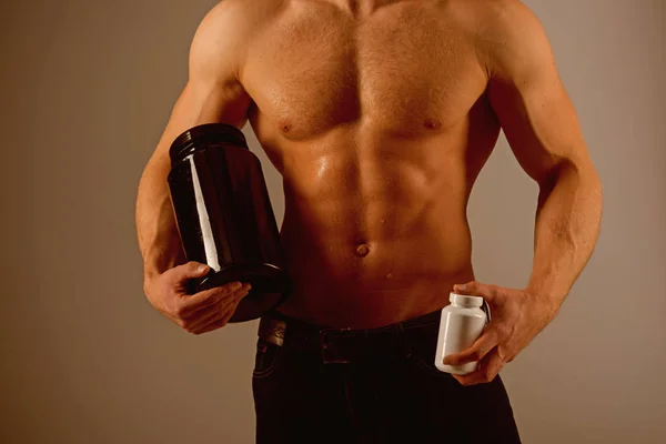 Transforming body with diet. Anabolic hormone increases muscle strength. Strong man hold vitamin bottles. Man with six pack abs. Muscle growing with anabolic steroids. Vitamin nutrition. Healthy diet — Stock Photo, Image