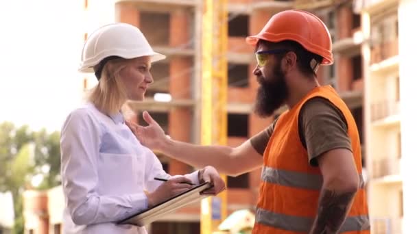 Byggare i Skyddshjälmar diskutera på byggarbetsplatsen. Byggare på byggarbetsplatsen. Två ingenjör har consulting möte på byggarbetsplats. — Stockvideo
