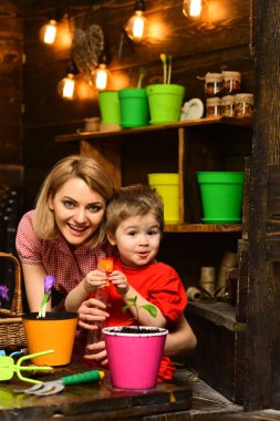 Gübre kavramı. Küçük çocuk ve kadın gübre genç bitki tencerede. Anne ve oğlu gübre üzerinde yeni yeşil bitki sprey. Organik gübre