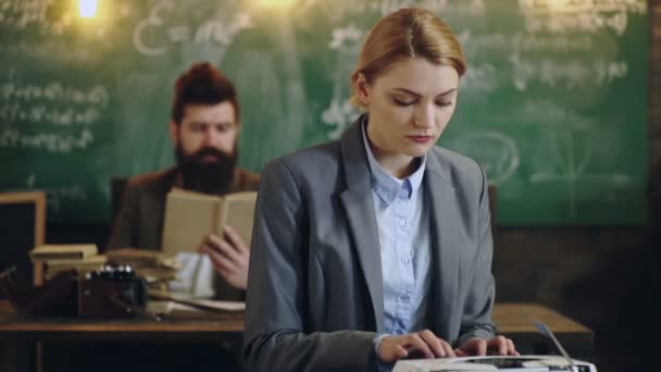 Donna che indossa vestito testo dattilografia sulla macchina da scrivere sullo sfondo del consiglio scolastico e libro di lettura uomo. Persone intelligenti lavorano in una classe scolastica sullo sfondo di bordo verde. Concetto di apprendimento . — Video Stock