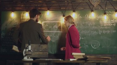Sakallı Profesör ve kız öğrenci kara tahta yazılan formüller karar. Profesör ve öğrenci kara tahta yanında. Öğrenme kavramı. Profesör sırasında olan bir Tebeşir tahtaya yazma.
