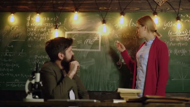 女子生徒が受かります。教師と生徒。学校に戻る眼鏡とひげを生やした先生は、数学上の式を解決するために学生の女の子を教えています。学習のコンセプト — ストック動画