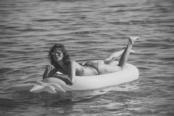 Csinos lány gumimatrac ananász formájú, az óceán, tenger, úszás a Stilusos bikinit, és napszemüveget visel. Nyaralás és pihenés fogalmát. Nő van pihenés, nyugi, feküdjön alakú matrac levegő-ananász. — Stock Fotó
