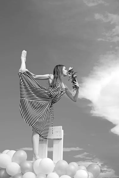 Retrato de mujer de moda. chica con flores se sientan en el cielo. sintiendo libertad y soñando. inspiración e imaginación. mujer en vestido de verano con globos de fiesta. acrobacias y deporte. spli — Foto de Stock