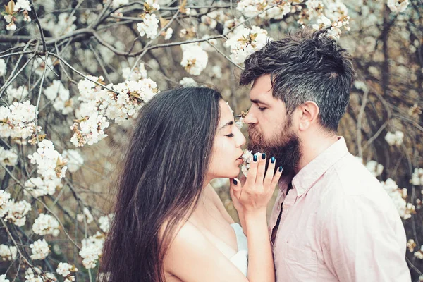 Concepto de fecha de primavera. El hombre y la mujer se abrazan en el jardín floreciente en el día de primavera. Pareja enamorada pasar tiempo en el jardín de primavera, ramas con flores en el fondo. Un par de abrazos cerca de árboles florecientes —  Fotos de Stock