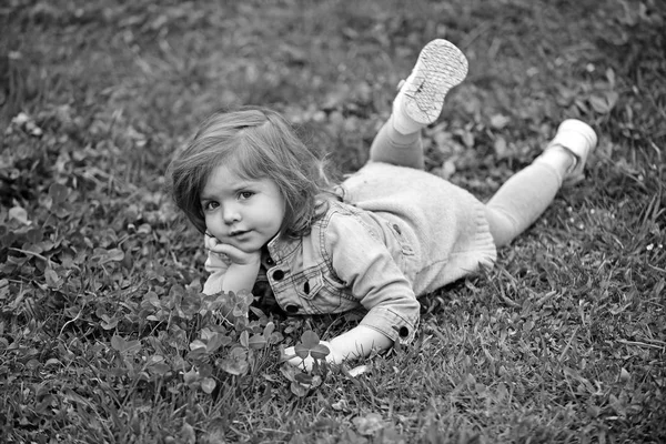 Pequeña chica encantadora se encuentran en la hierba verde —  Fotos de Stock