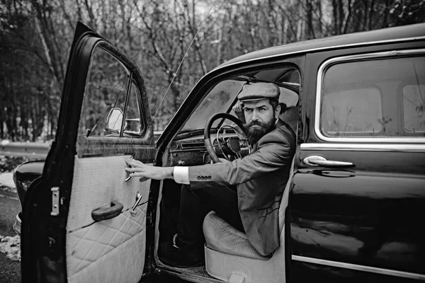 Travel and business trip or hitch hiking. Escort man or security guard. Call boy in vintage auto. Bearded man in car. Retro collection car and auto repair by mechanic driver