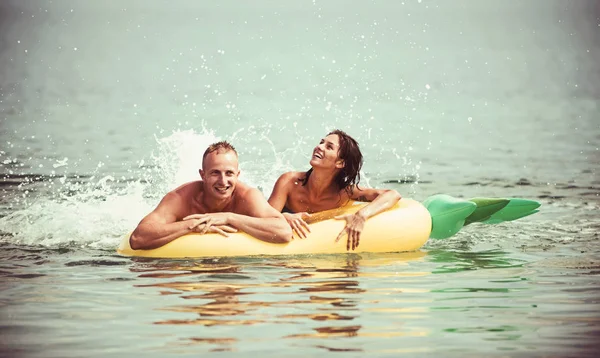 Vacaciones de verano y viajes al océano. Pareja en el amor baño de sol en la playa en el colchón de aire. Colchón inflable de piña, alegría de la actividad. Maldivas o agua de playa de Miami. Sexy feliz pareja en el mar Caribe — Foto de Stock