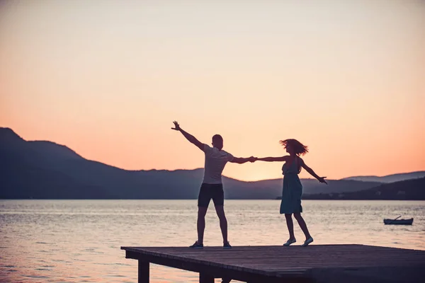 Fille et l'homme dansent à l'eau de mer au coucher du soleil. fille et homme dansant au crépuscule . — Photo