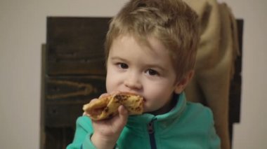 Lezzetli pizza yiyen bir çocuk, yakın çekim. Sağlıklı gıda kavramı. Küçük çocuk bir dilim pizza sahip. Pizza partisi.
