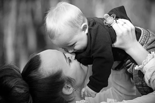 Família feliz desfrutar de dia ensolarado. Mãe beija o filhinho com amor. A mulher brinca com a criança. Mãe e menino ao ar livre. Conceito do dia das mães. Amor cuidado e confiança — Fotografia de Stock