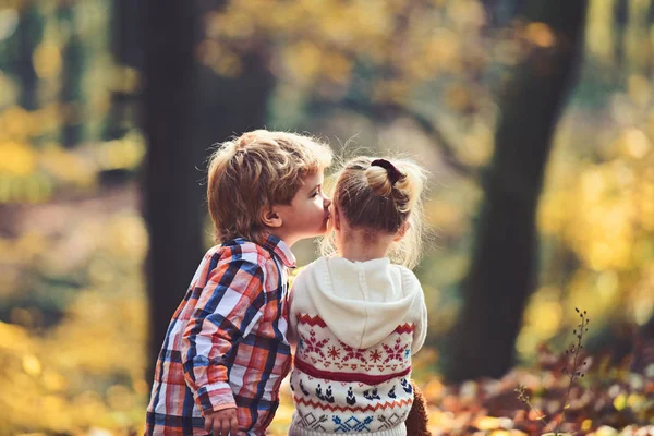 Niño pequeño beso niña amiga en el bosque de otoño. Hermano besa a hermana con amor en el bosque. Concepto de San Valentín. Amor y confianza familiar. Amistad infantil y desarrollo temprano de los niños —  Fotos de Stock