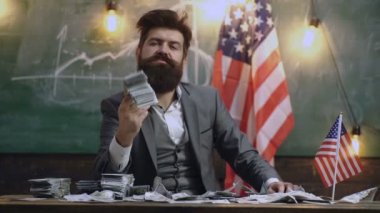 Sakallı adam Amerikan bayrağı güçlü bir ABD Ekonomi temsil eden arka plan karşı bir avuç dolar tutar. Zenginlik ve güç kavramı. Para ve Amerikan bayrağı. Vatanseverlik ve özgürlük.