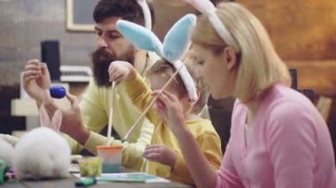 Anne, baba ve oğul resim yumurta vardır. Mutlu aile Paskalya için hazırlıyoruz. Mutlu paskalyalar. Sevimli küçük çocuk çocuk bunny kulaklar giyiyor. Mutlu aile gülümseyen ve gülüyor, yumurta üzerinde çizim.