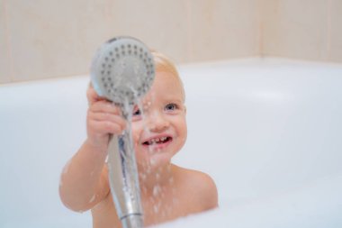 Tuvalette. Şapka içinde banyo köpüğüyle yıkanan küçük bir bebek. Küçük şirin çocuk yıkıyor. Çocuk temiz ve kuru havluyla.