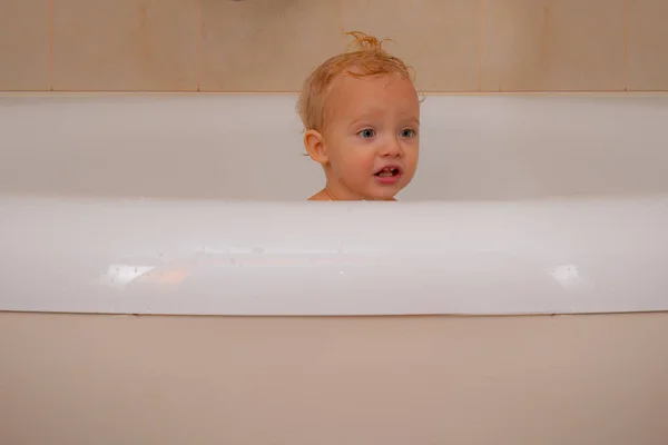 Baby with a towel after taking a bath. Bath. Funny blond kid boy having fun with water by taking bath in bathtub. — Stock Photo, Image