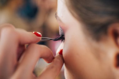 Kadın güzellik çehresi konsepti. Mükemmel makyajlı güzel bir kadın. Profesyonel bir makyöz stüdyoda kirpik modelleri çizer..