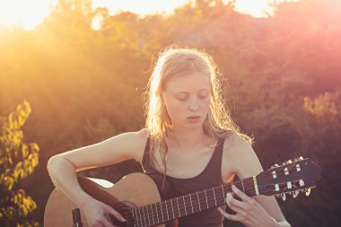 Alanında oturup ve gitar çalmak genç kadın
