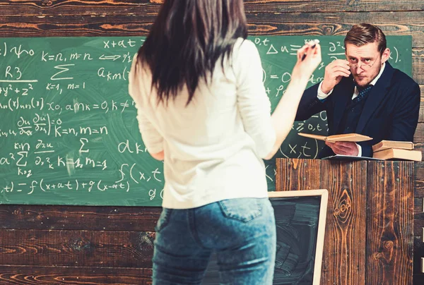 Vrid tillbaka brunett tjej framför professor. Strikt lärare tittar på hans kvinnlig student stående på talarstol — Stockfoto