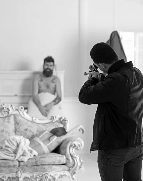 Man with gun aim at blur couple in bedroom. Killer hold sniper rifle in leather coat and jeans. Husband with weapon shoot cheating wife and lover. Love triangle concept. Cheating, jealousy and crime — Stock Photo, Image