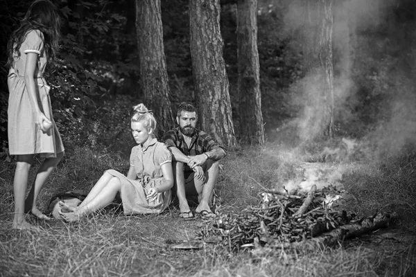 女性と男性では、ビンテージ スタイルのキャンプで火災します。友人はキャンプファイヤーでおくつろぎください。たき火で人々 は、緑の森を炎します。キャンプ、ハイキング、旅行。夏の休暇の概念 — ストック写真